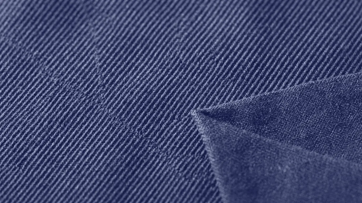 Macro close-up of grey gabardine with fine, tightly woven diagonal lines and a flat back side at the folded corner