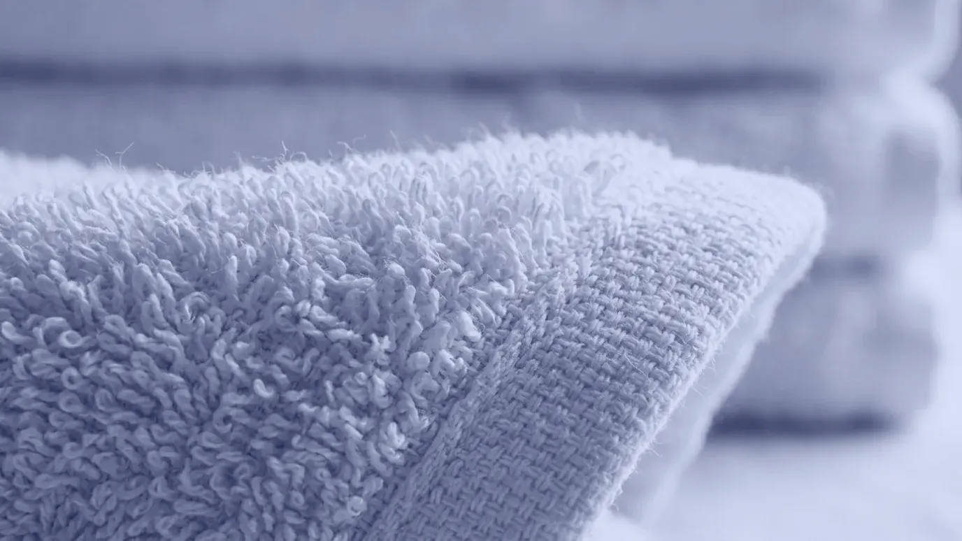 Macro close-up of white cotton terry cloth with uncut pile loops and the flat woven ground visible at the edge