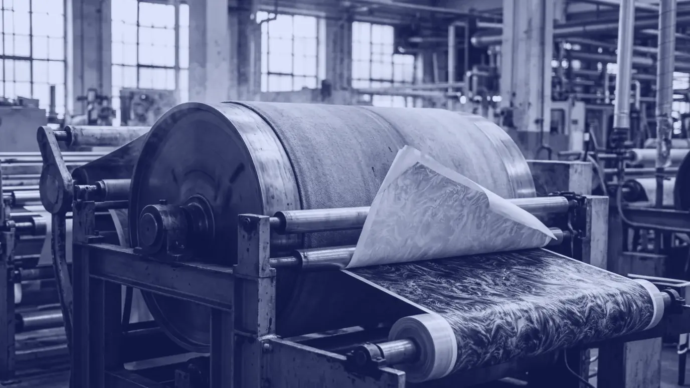 Fabric running through a heated drum transfer printing machine, a vivid pattern revealed as the paper peels away