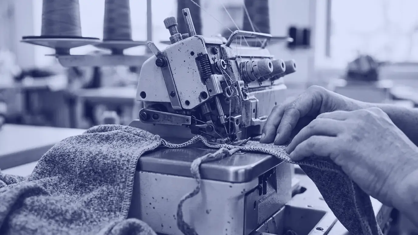 Industrial overlock machine stitching the edge of knit fabric, with needles, loopers and knife in close-up