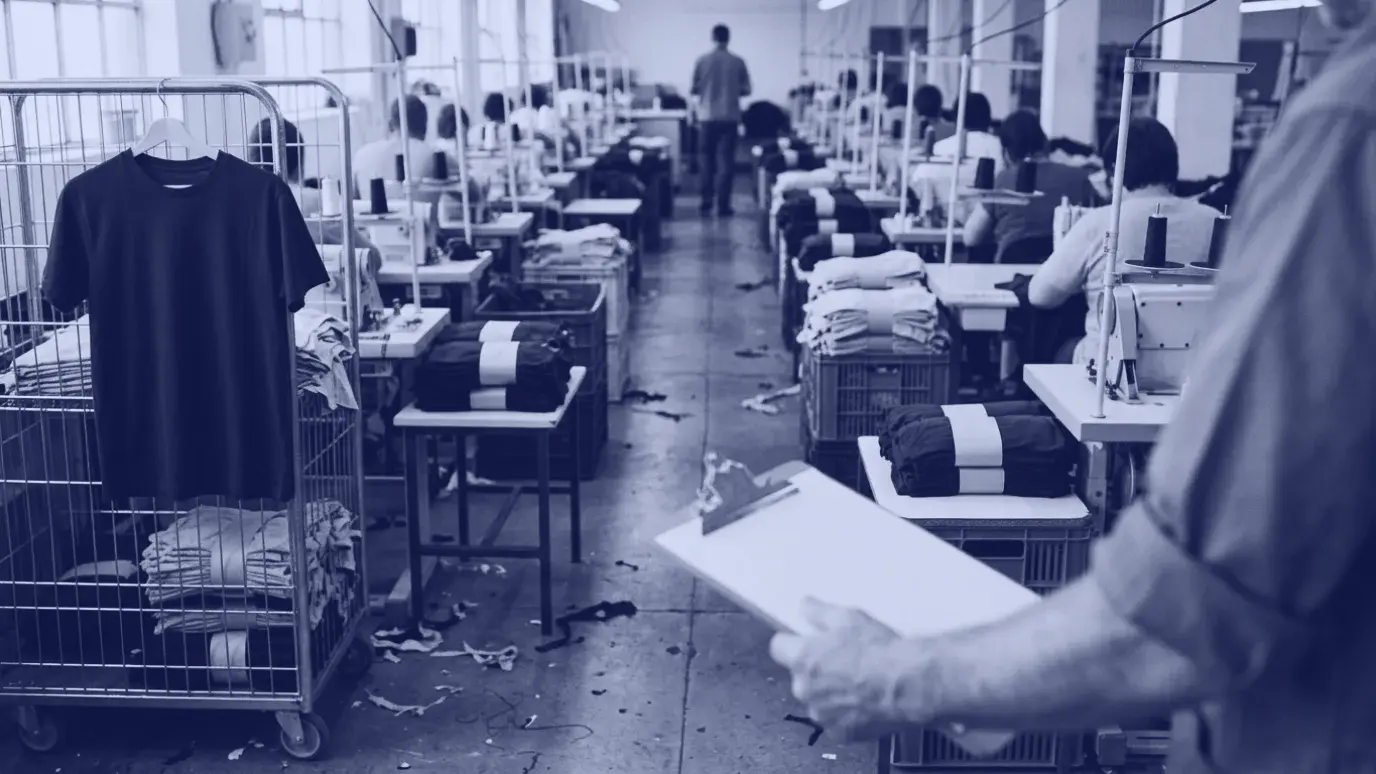 Dikim bandında iki sıra makine arasında bağlı kesim parçası desteleri; önde boş bir not tahtasını tutan el ve önkol